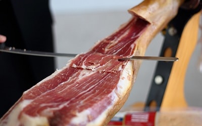 Man Cutting a Slice from a Serrano Ham