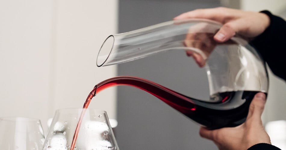 Man Pouring Red Wine from a Swan Decanter into a Glass