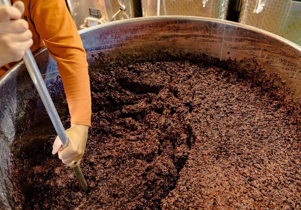 Worker Stirring Fermenting Wine Grapes