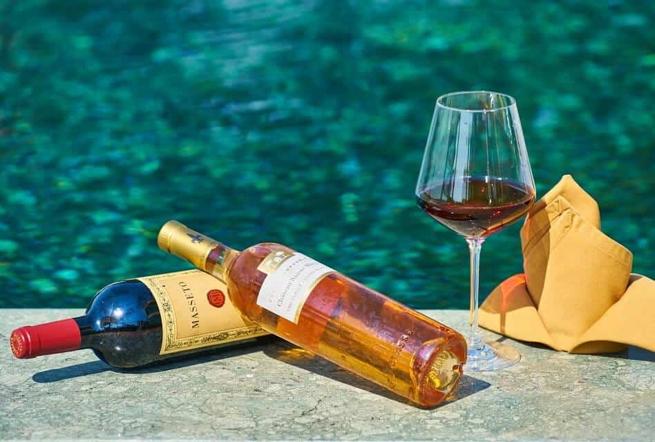Wine Bottles and Glass close to Swimming Pool