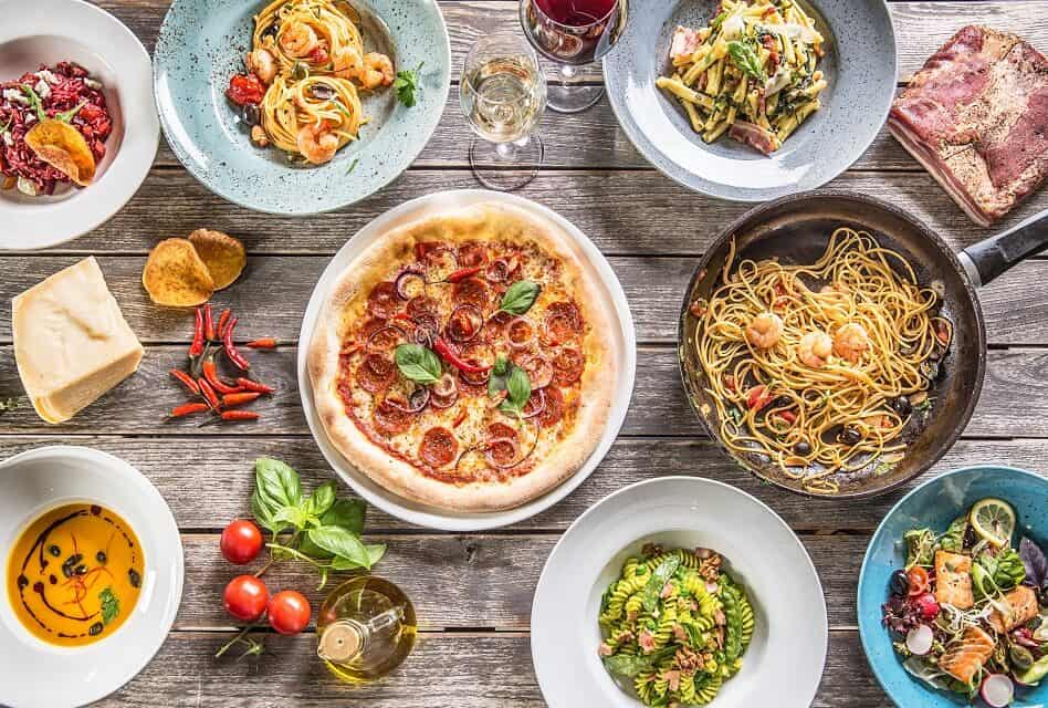 Multiple plates of Italian Food and Wine Glasses